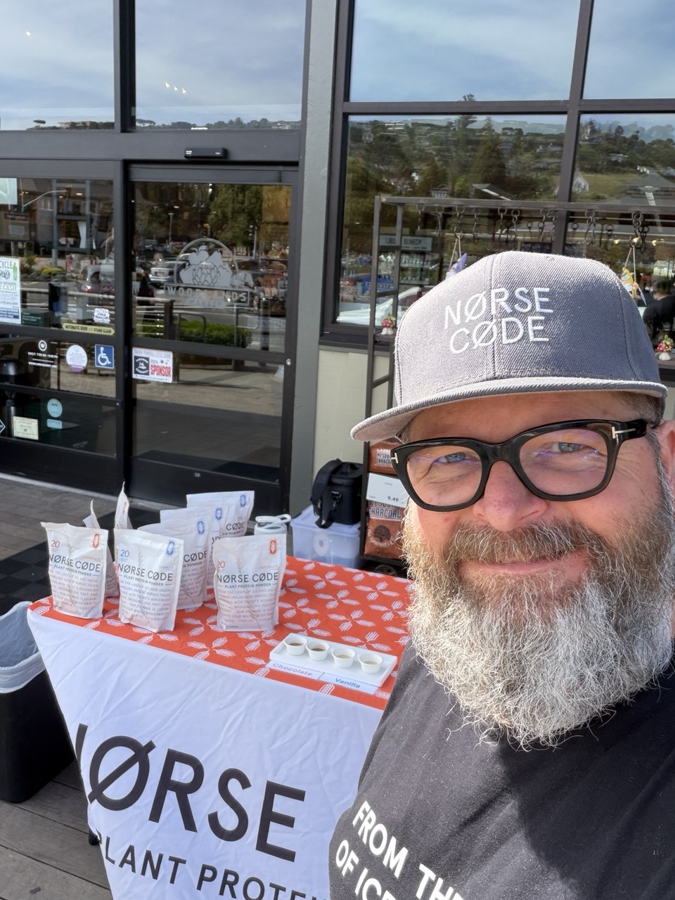 Smári at a NØRSE CØDE sampling table outside a retail demo